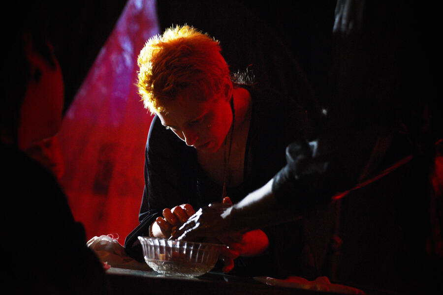 Red examines Rains hand as they wash it with great care in a crystal bowl. 