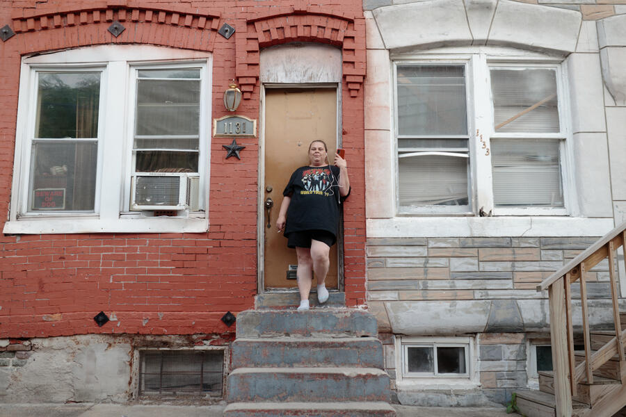 A woman poses for a portrait outside a rowhome in Pigtown.