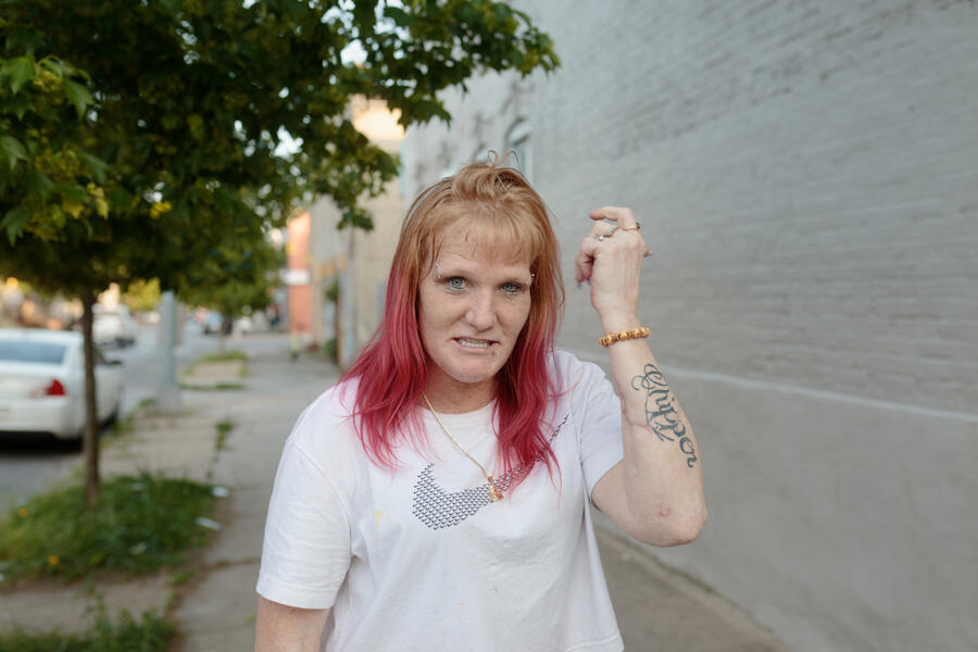 A woman poses for a portrait and shows off her newly dyed pink hair in Pigtown.