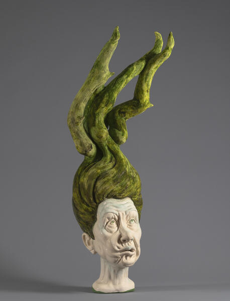 Large sculpted head with green hair like horns