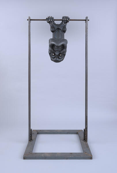 Double headed figure hanging from metal bar