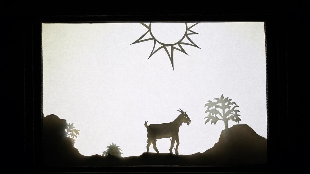 A shadow puppetry landscape with a goat, a coffee bush and a blazing sun