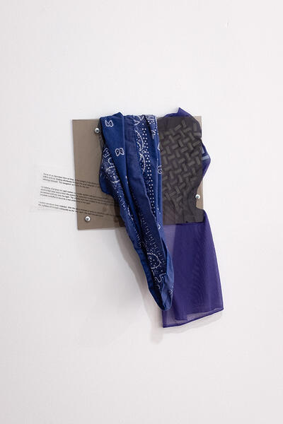 Flagging color study #1, 2025. Bandana, plexiglass, mesh, used hospital sock, transparency sheet, silicone, hardware 23”x18”