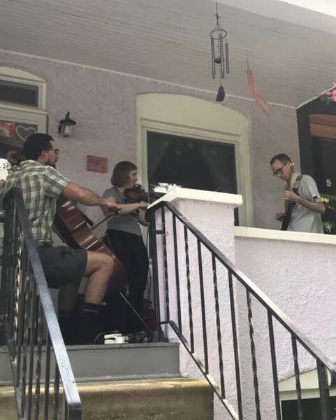 Inc, Inc, Inc performing on a porch in Hampden