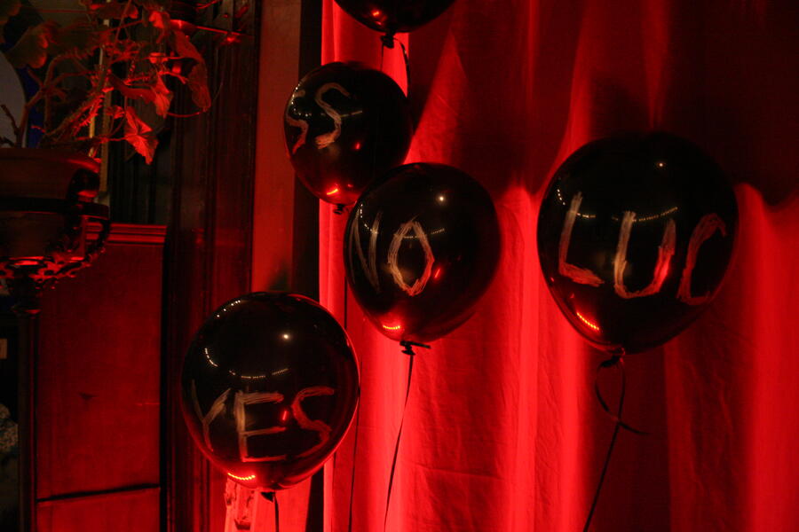 Five black balloons with words written on them in gold.