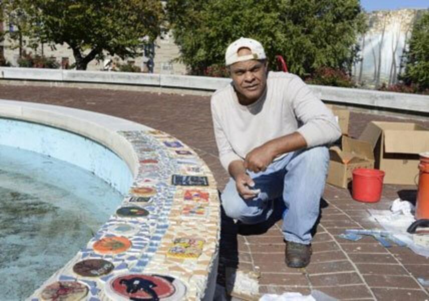 The photograph shows artist Herb Massie next to the Tiffany Square mosaic tiled wall.