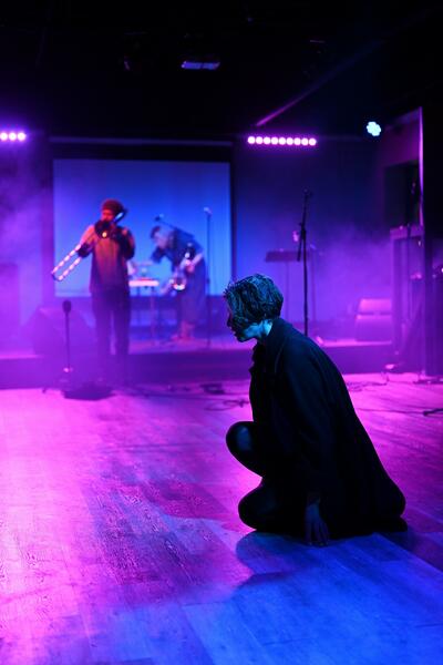 three performers under purple light