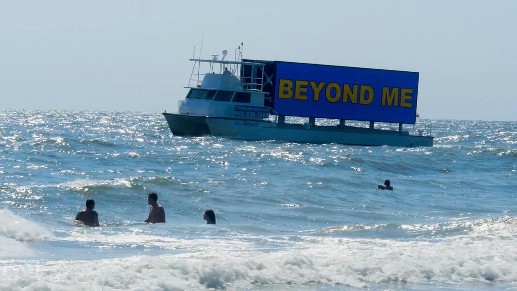 boat in ocean with LED screen that reads 'Beyond Me'