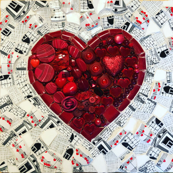 Mosaic made with broken dishes and found objects depicting a red heart with a background of black and white