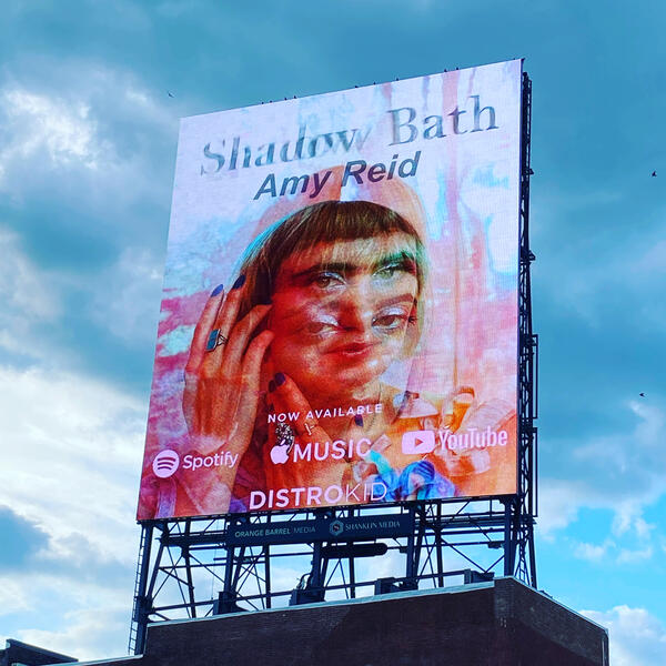 Cover art image on a billboard with clouds in the background