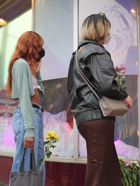 two people holding flowers outside of a window installation