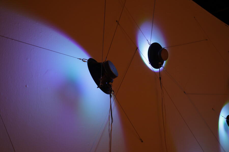 detail of a speaker hung just in front of a wall, with LEDs inside the cone illuminating the wall