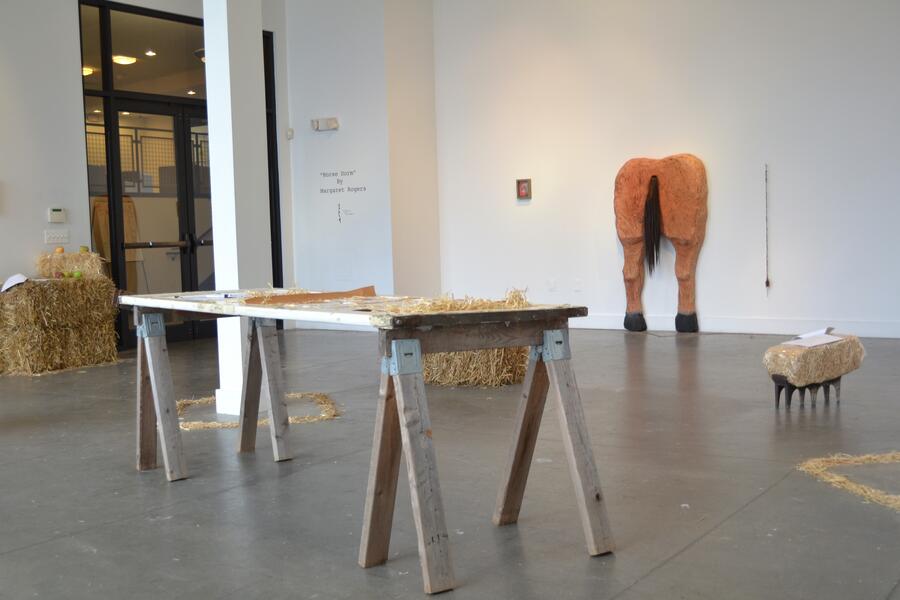Installation view, table, horse butt, haystacks, scripts
