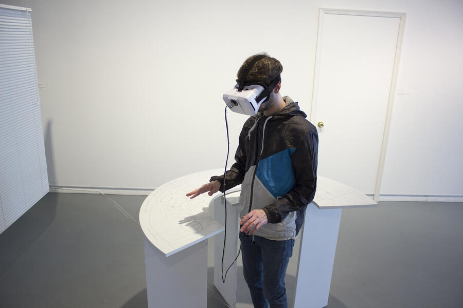 Person using virtual reality headset in a white gallery space with circular table beside them