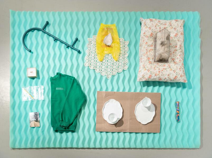 Found objects arranged neatly on top of a turquoise mattress topper, viewed from above