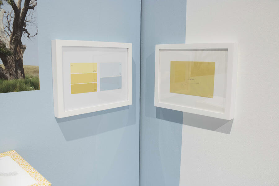 Two frames with yellow objects inside placed next to each other in a corner painted blue