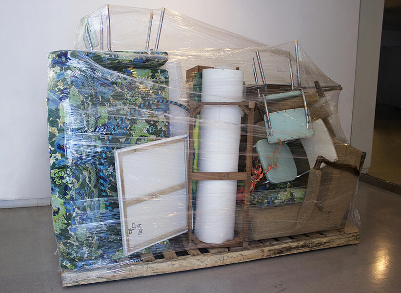 Furniture and Art stacked on top of a moving pallet and wrapped in clear plastic