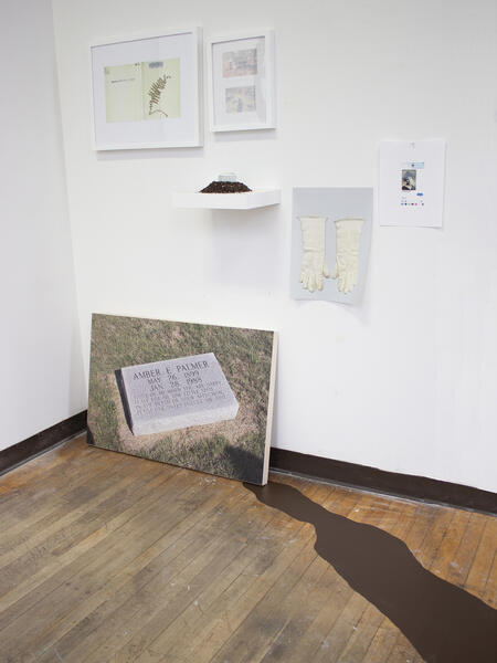 Framed objects and photographs installed on white wall with brown shadow on the ground