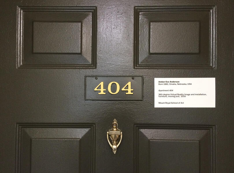 Closeup of a door with the numbers 404 in the center and a gallery label to the right