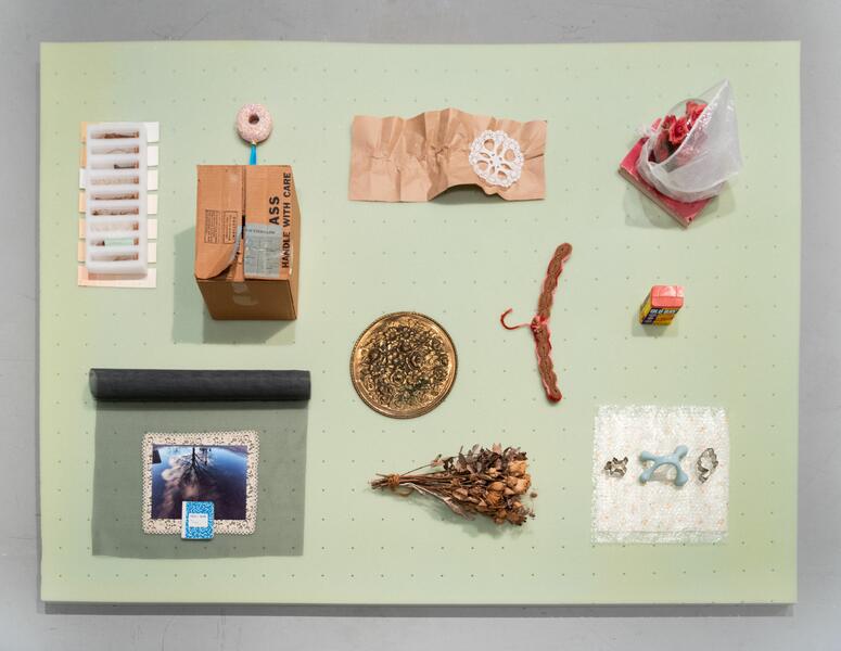 Found objects arranged neatly on top of a green tea-colored mattress topper, viewed from above