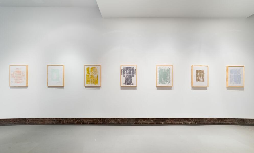 Row of colorful prints in wooden frames on a white gallery wall